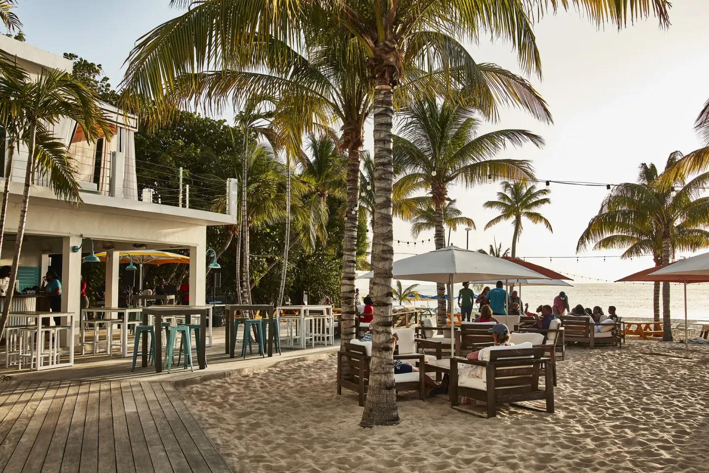 Beach bar seating and palm trees beside the sand at Malliouhana Resort Anguilla.