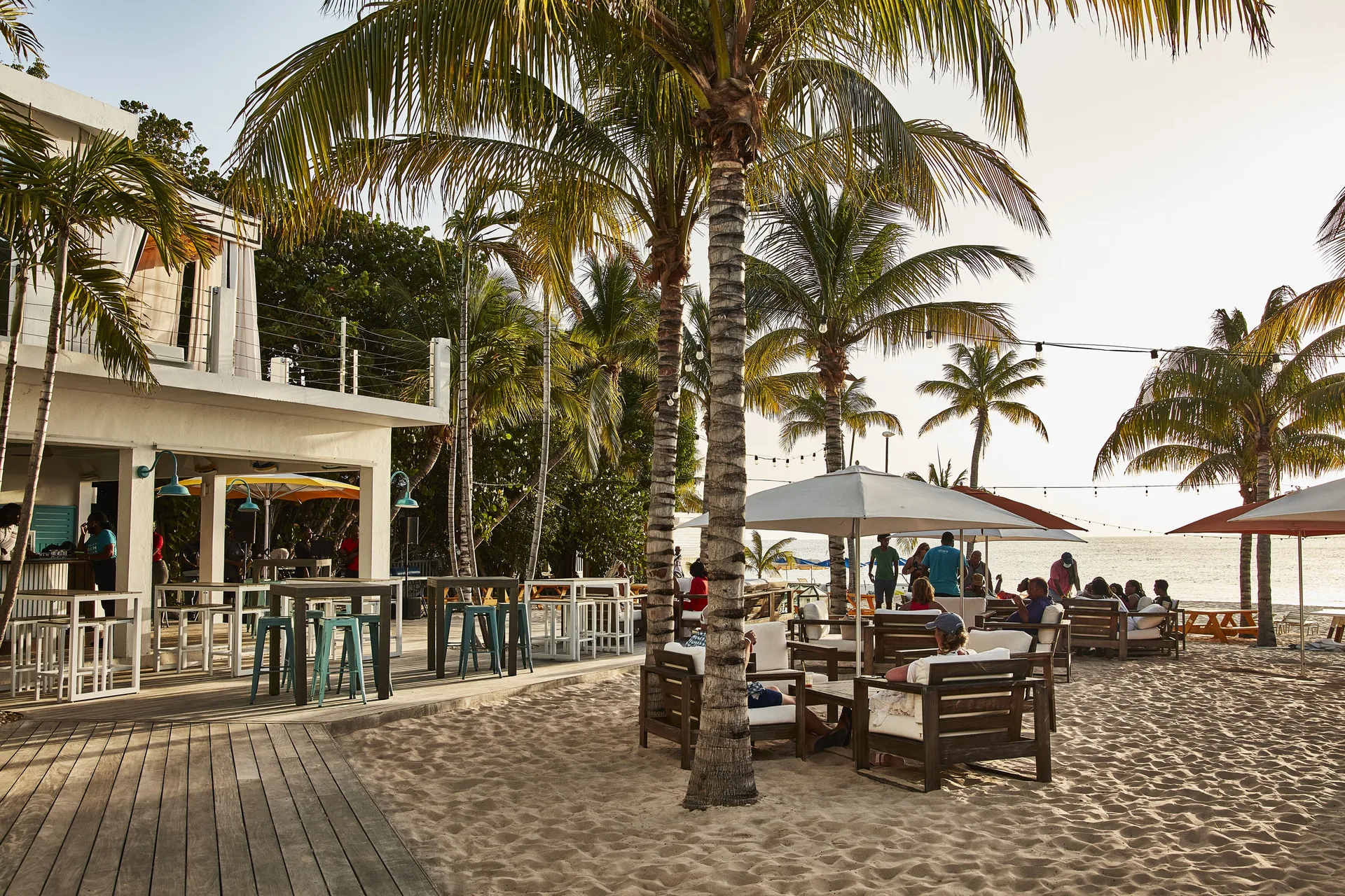 Beach bar seating and palm trees beside the sand at Malliouhana Resort Anguilla.