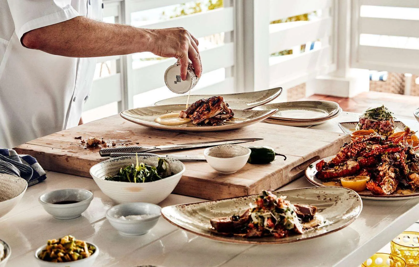 Chef plating grilled dishes on a counter at Malliouhana Resort Anguilla.