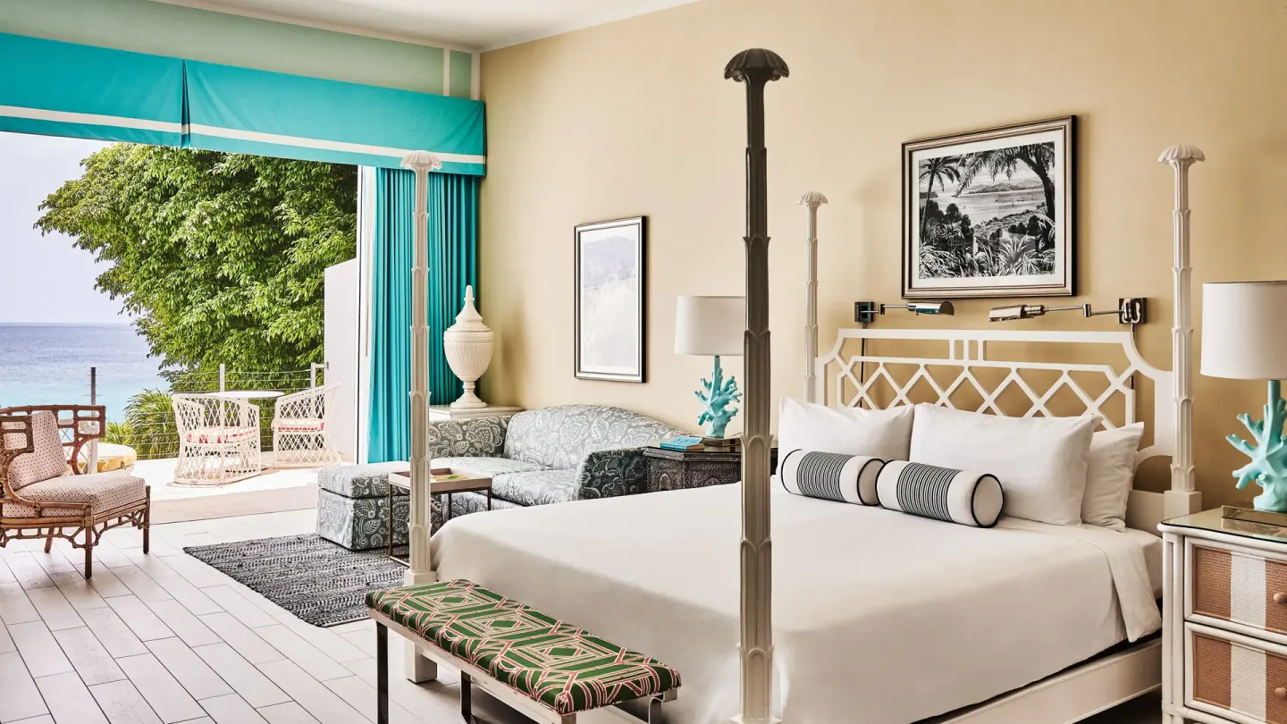 Turtle Cove Suite king bed with sofa and terrace beyond at Malliouhana Resort Anguilla.