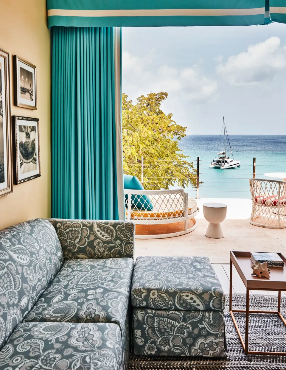 Turtle Cove Suite sofa looking onto a terrace and sailboat at Malliouhana Resort Anguilla.