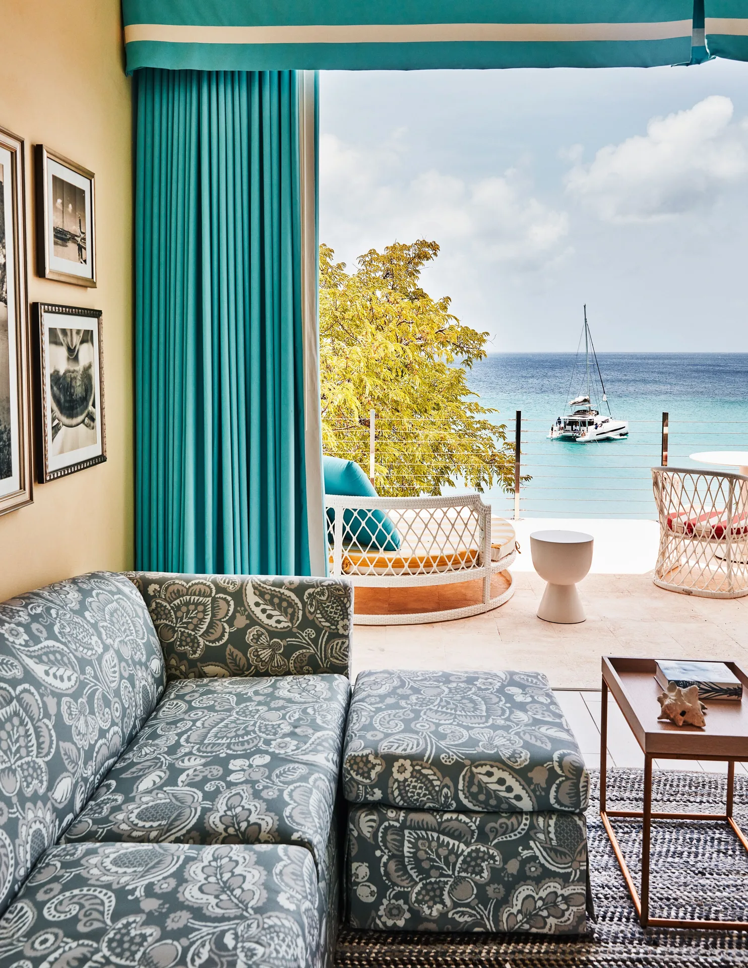 Turtle Cove Suite sofa looking onto a terrace and sailboat at Malliouhana Resort Anguilla.
