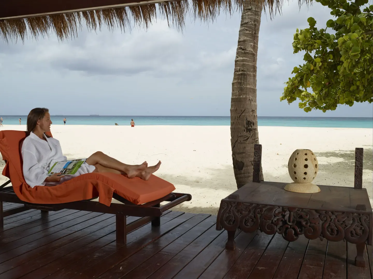 Guest relaxing on an orange lounge by the beach at Manchebo Beach Resort and Spa.