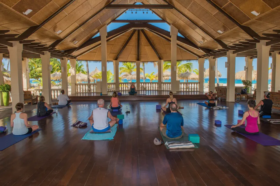 Group yoga class in an open pavilion by the beach at Manchebo Beach Resort and Spa.