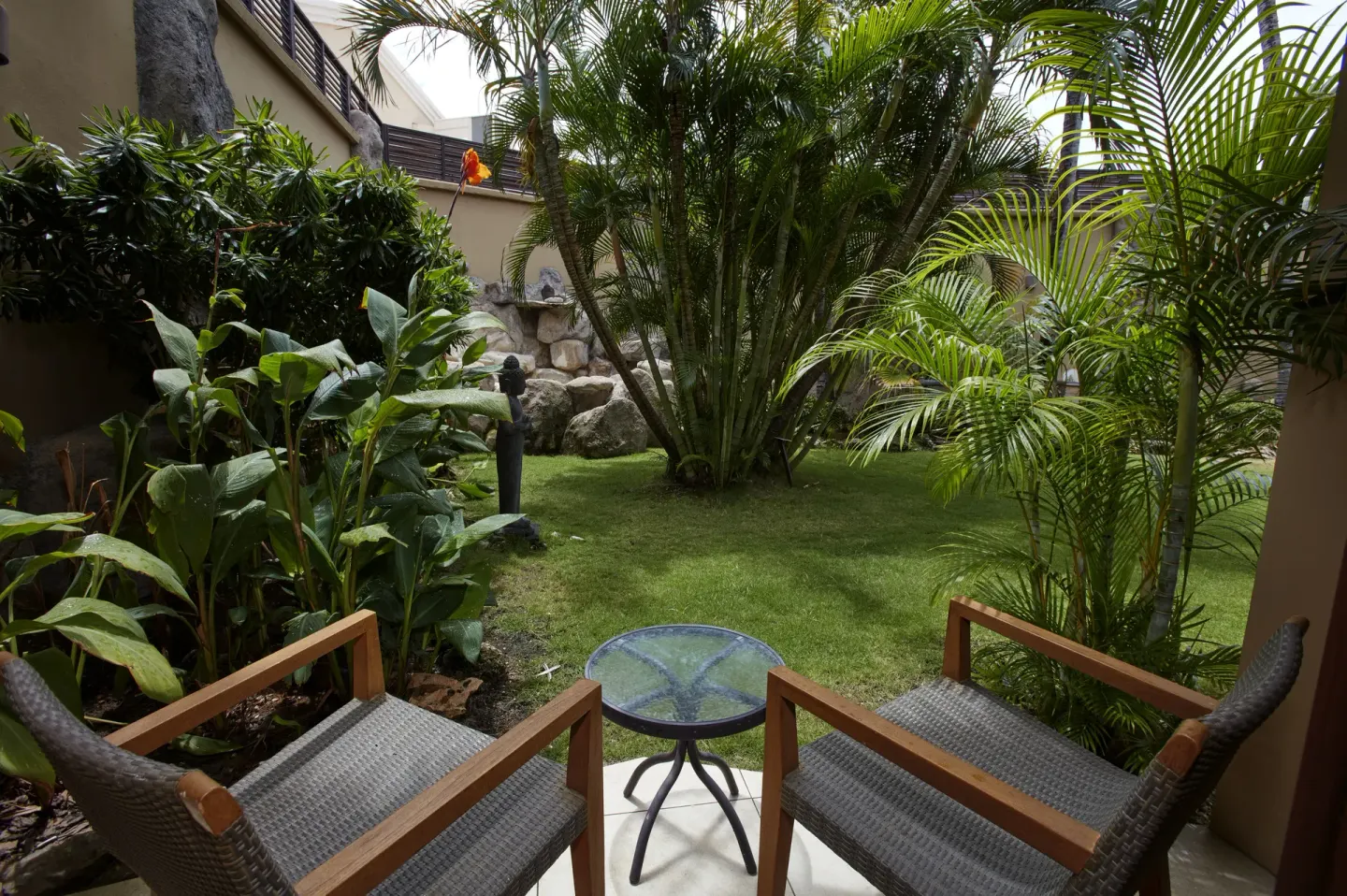 Patio chairs and a small table facing tropical garden plants at Manchebo Beach Resort and Spa.