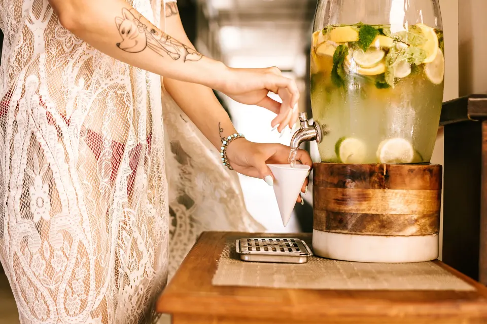 Guest filling a cup from a citrus water dispenser at Manchebo Beach Resort and Spa.