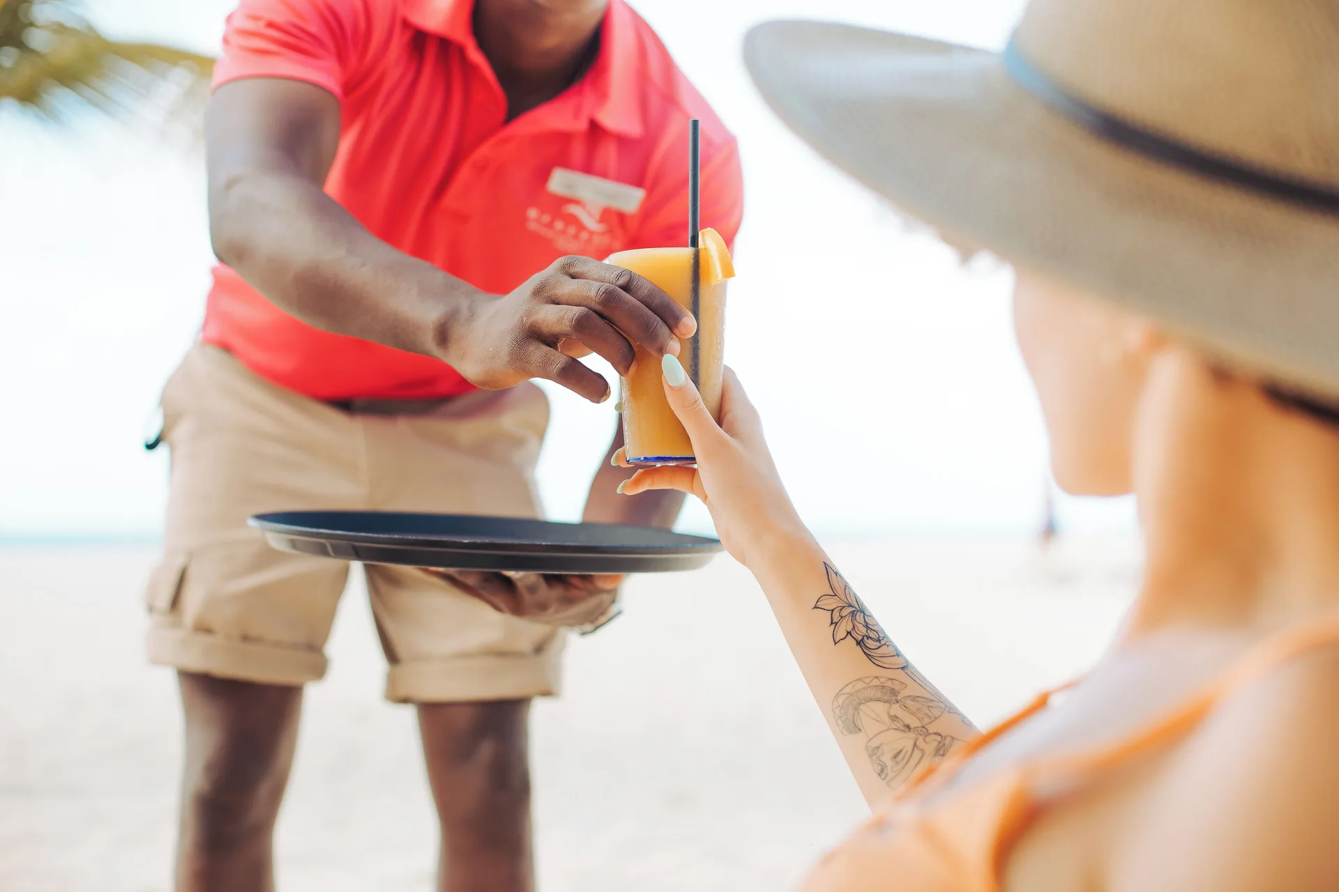 A beach server hands a tropical drink to a guest at Manchebo Beach Resort and Spa.