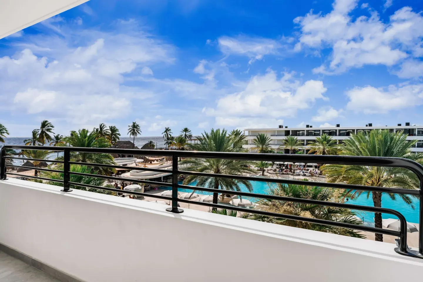 Balcony view of the pool, palms and sea at Mangrove Beach Corendon Curacao Resort.