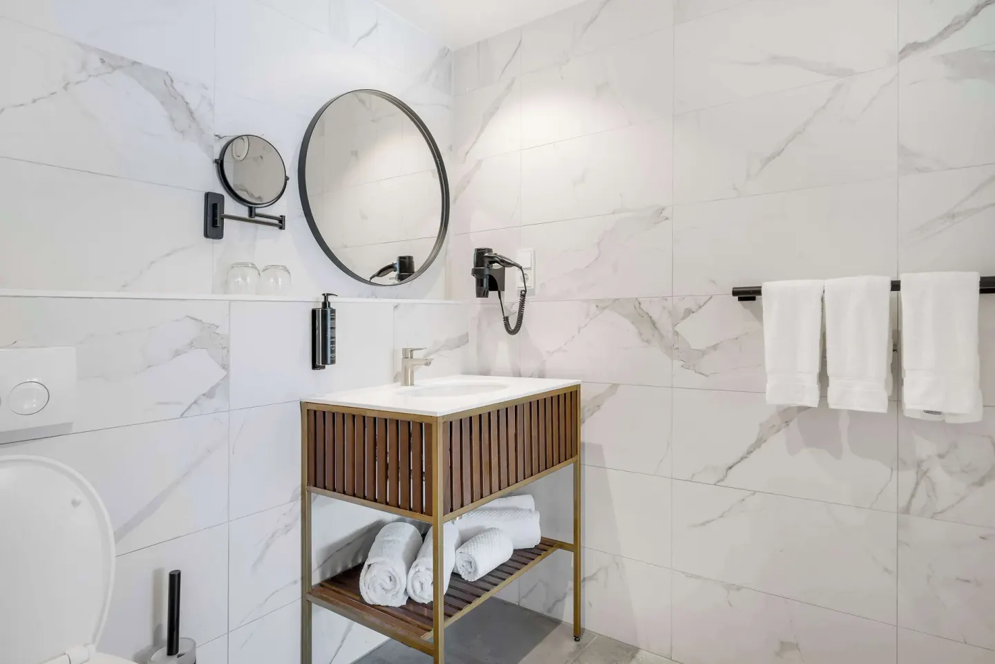Bathroom vanity with round mirror and towels at Mangrove Beach Corendon Curacao Resort.