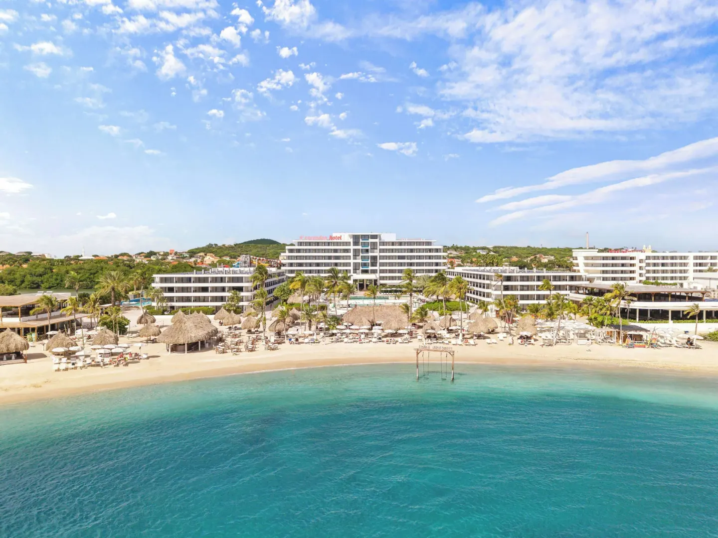 Resort buildings behind a sandy beach and turquoise sea at Mangrove Beach Corendon Curacao Resort.