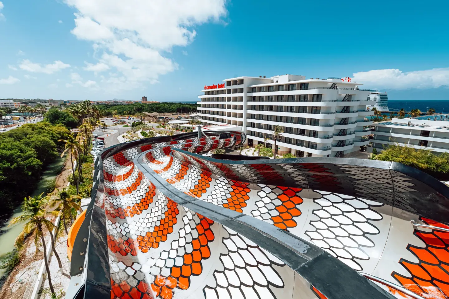 Elevated waterslide curves past resort buildings at Mangrove Beach Corendon Curacao Resort.