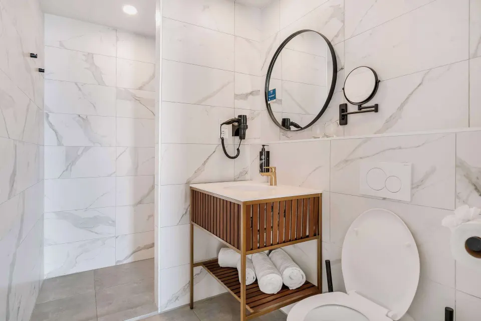 Guest bathroom at Mangrove Beach Corendon Curacao Resort with open shower, vanity, and toilet.