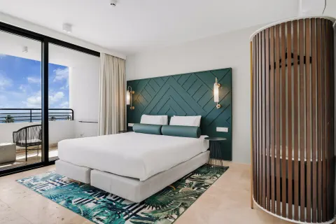 King bed guest room with balcony doors at Mangrove Beach Corendon Curacao Resort.