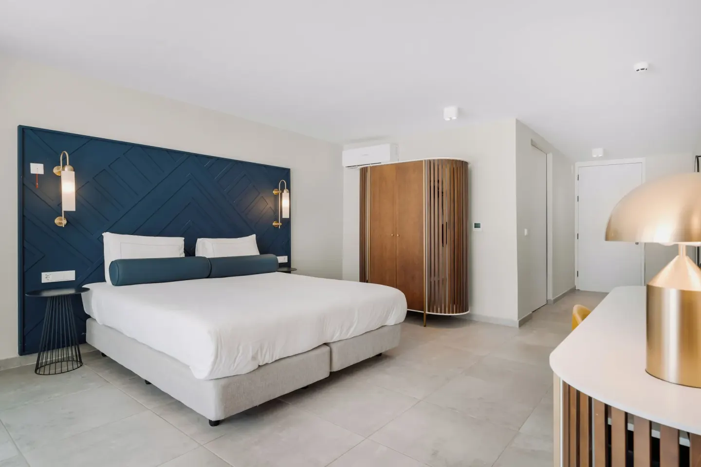King bed guest room with curved wardrobe and desk lamp at Mangrove Beach Corendon Curacao Resort.