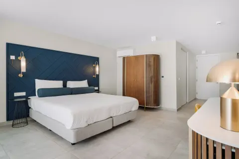 King bed guest room with curved wardrobe and desk lamp at Mangrove Beach Corendon Curacao Resort.