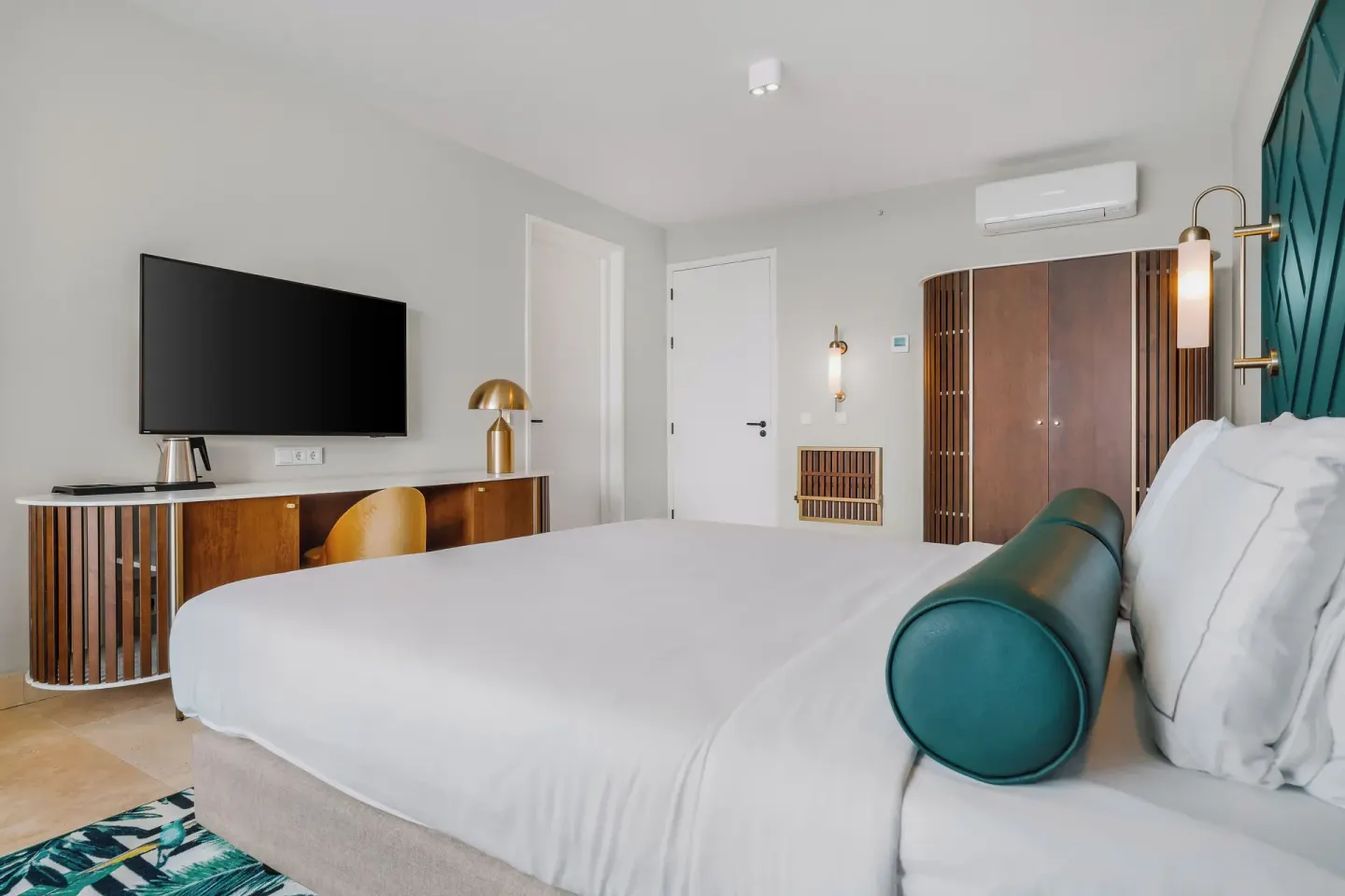 King bed, TV, desk, and wardrobe in a guest room at Mangrove Beach Corendon Curacao Resort.