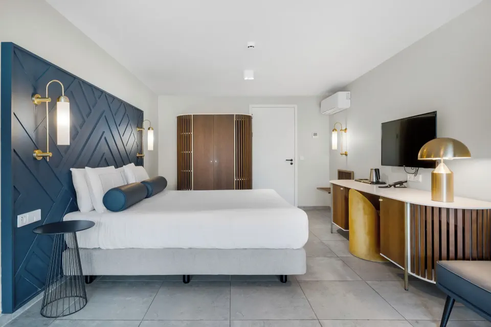 King bed guest room with blue headboard at Mangrove Beach Corendon Curacao Resort.
