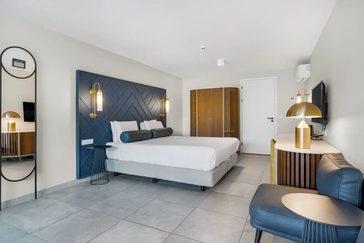 King bed guest room with mirror, desk and lounge chair at Mangrove Beach Corendon Curacao Resort.