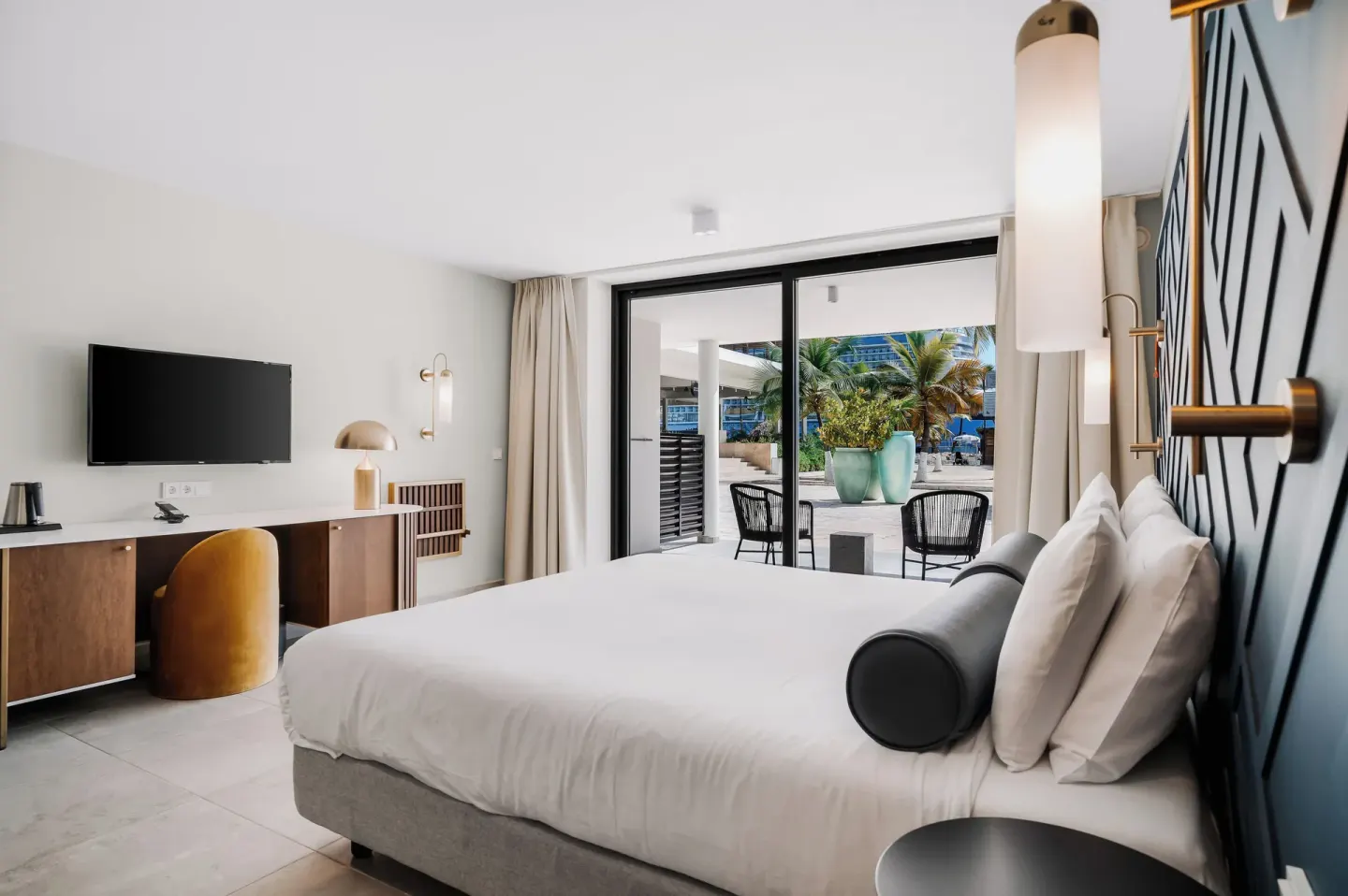 King bed guest room with patio doors and resort grounds outside at Mangrove Beach Corendon Curacao Resort.