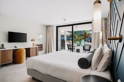 King bed guest room with patio doors and resort grounds outside at Mangrove Beach Corendon Curacao Resort.