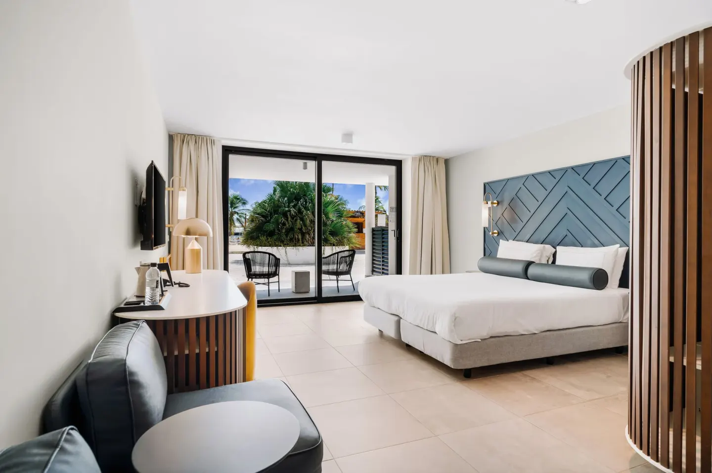 King bed guest room with terrace seating and palm views at Mangrove Beach Corendon Curacao Resort.