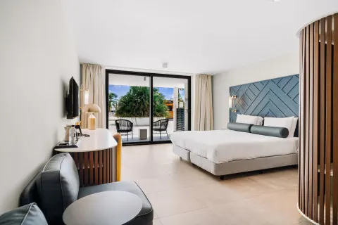 King bed guest room with terrace seating and palm views at Mangrove Beach Corendon Curacao Resort.