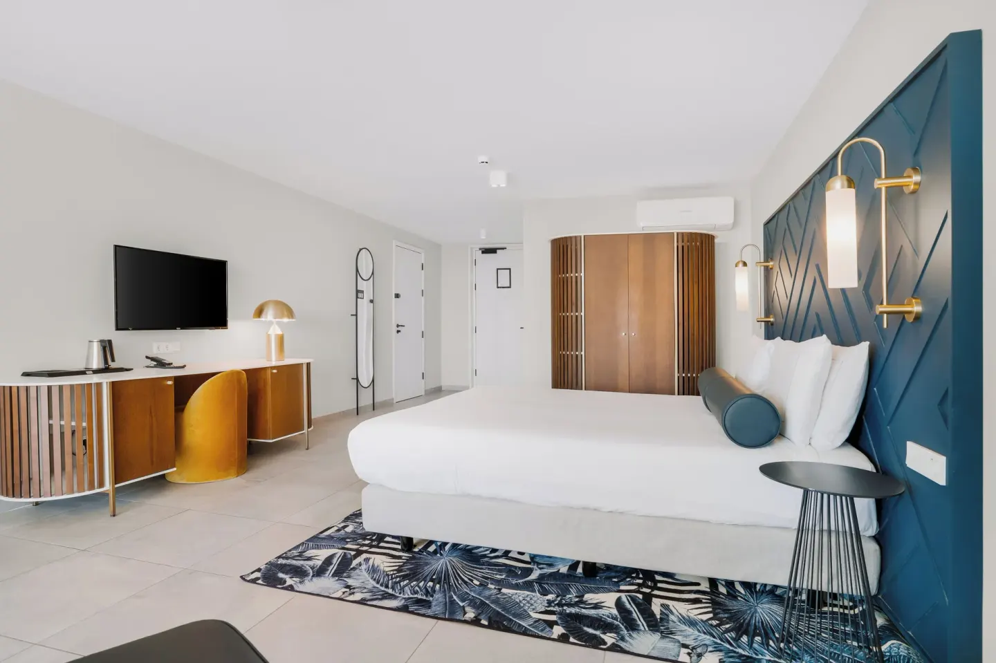King bed guest room with patterned rug and desk at Mangrove Beach Corendon Curacao Resort.