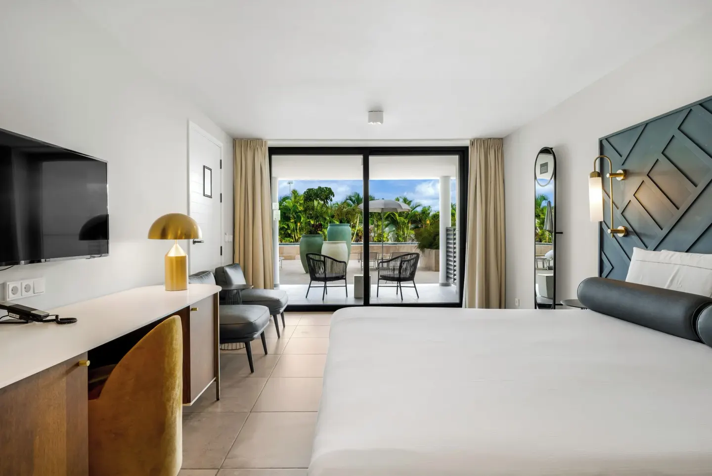 King bed guest room opening to a furnished terrace at Mangrove Beach Corendon Curacao Resort.