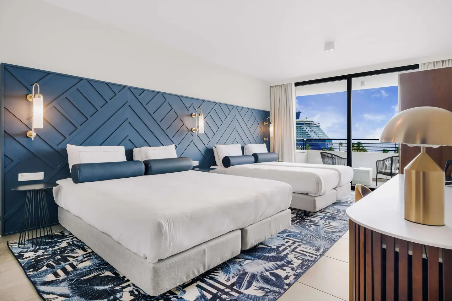 Two beds and balcony seating in a guest room at Mangrove Beach Corendon Curacao Resort.