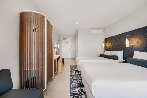 Two-bed guest room with wardrobe and entry view at Mangrove Beach Corendon Curacao Resort.