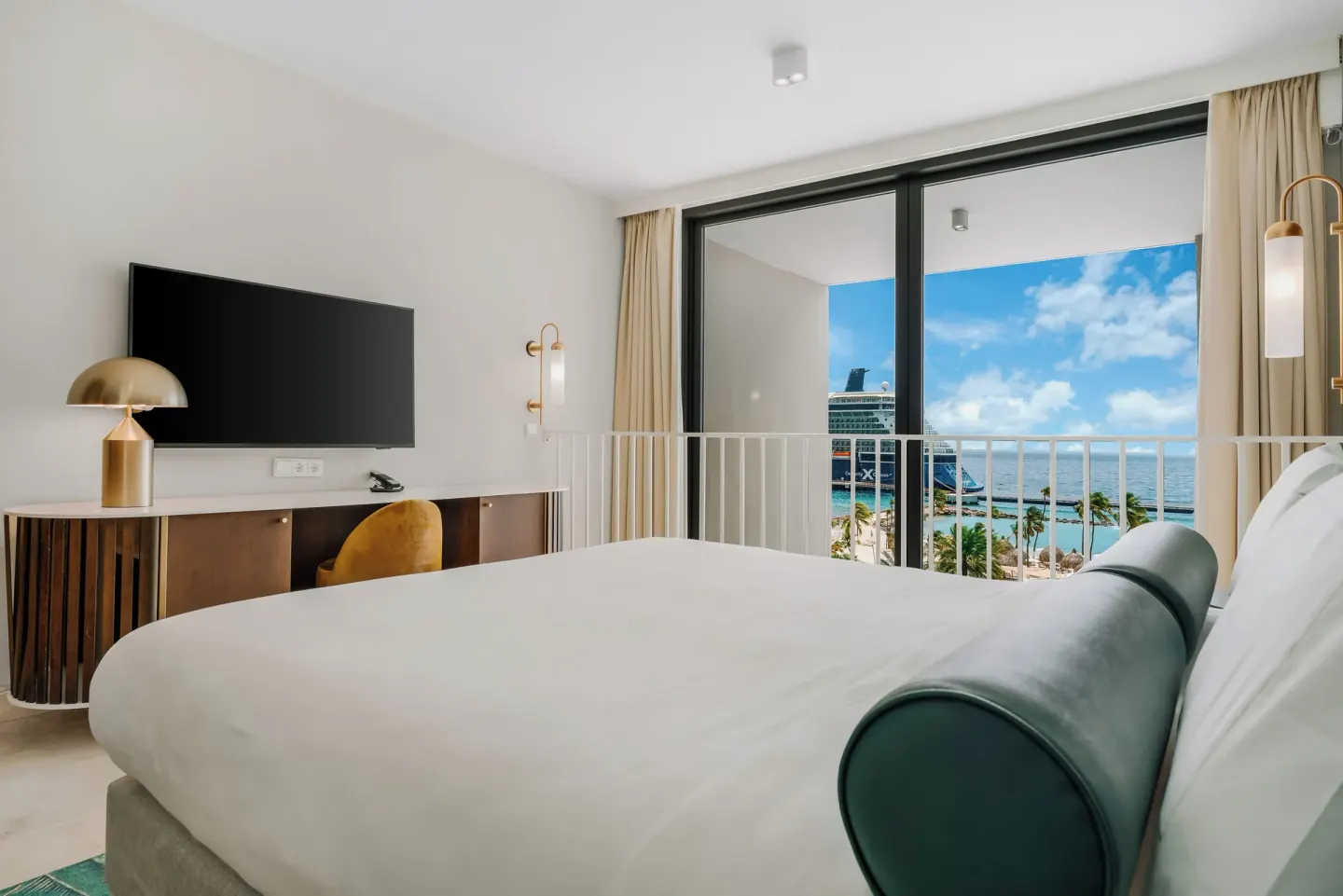 King bed guest room facing ocean-view balcony at Mangrove Beach Corendon Curacao Resort.