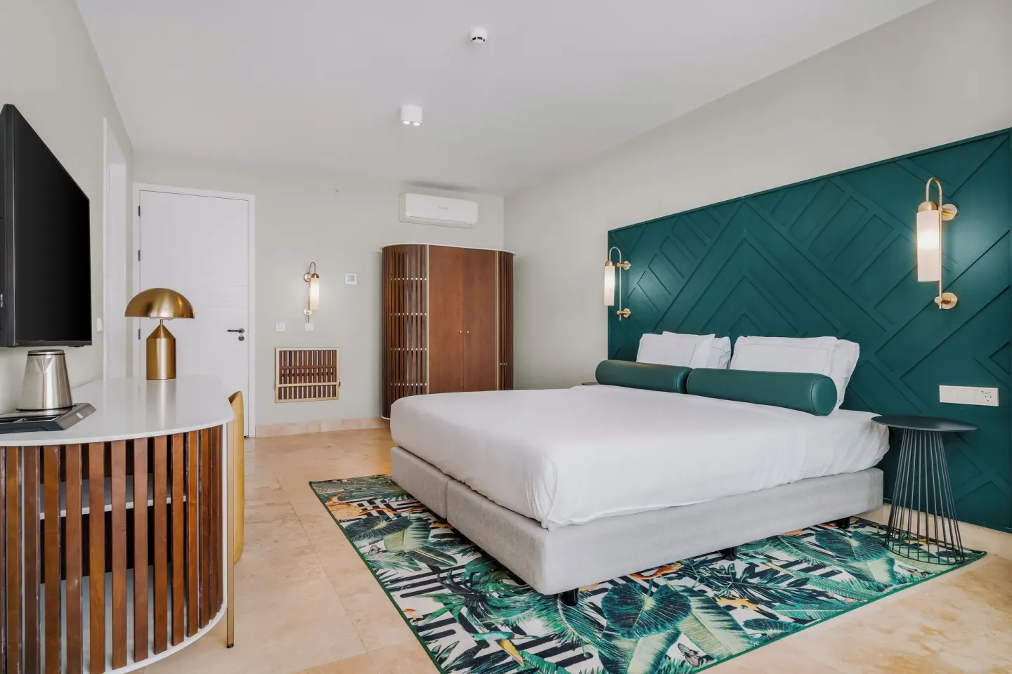 Teal-accented king guest room with wardrobe and desk at Mangrove Beach Corendon Curacao Resort.