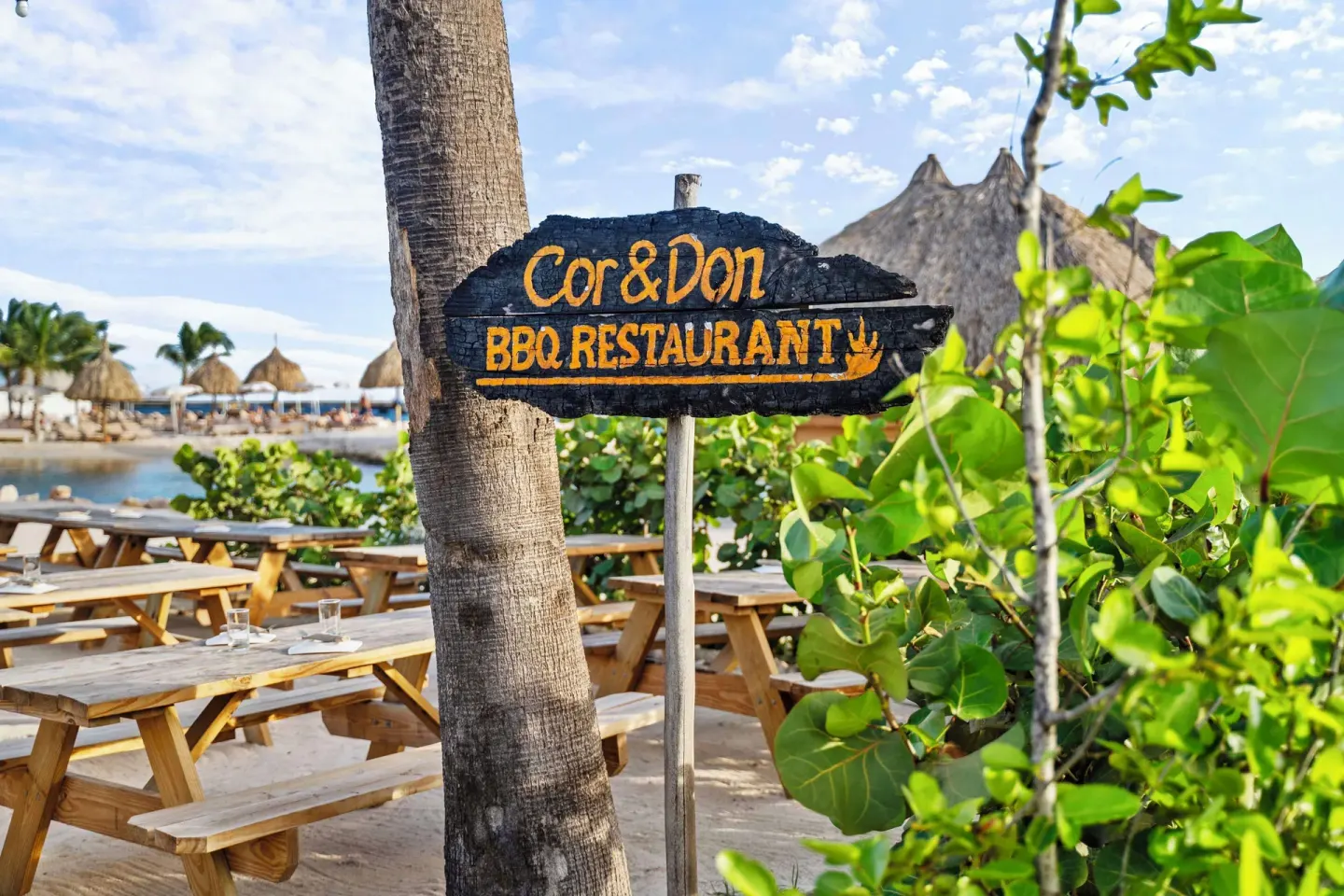 Cor & Don BBQ Restaurant sign by beach tables at Mangrove Beach Corendon Curacao Resort.