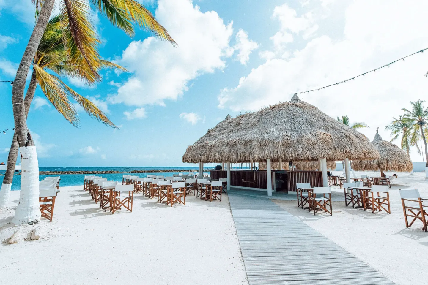 Beach bar with thatched roof and seaside tables at Mangrove Beach Corendon Curacao Resort.