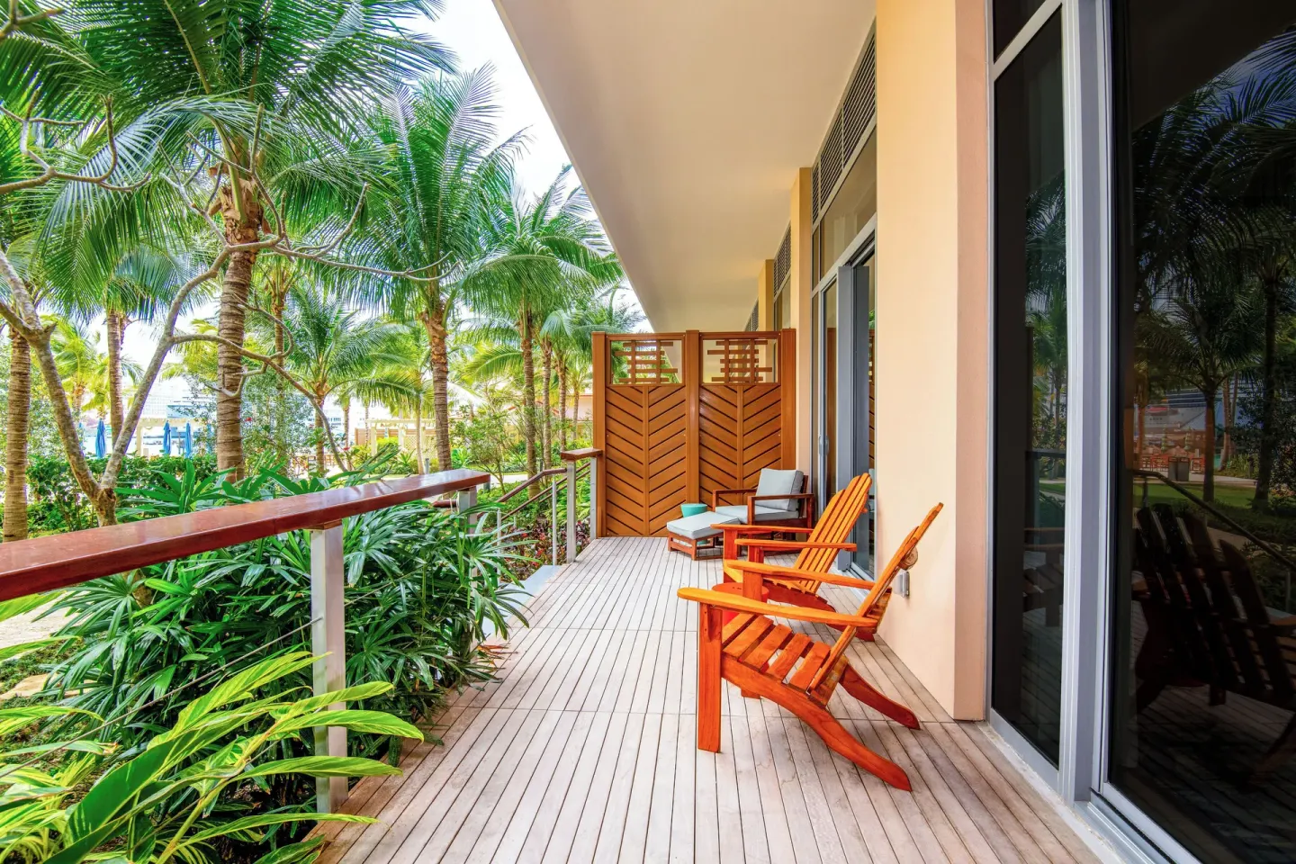 Ground-floor balcony with wooden chairs and palms at Margaritaville Beach Resort - Nassau.