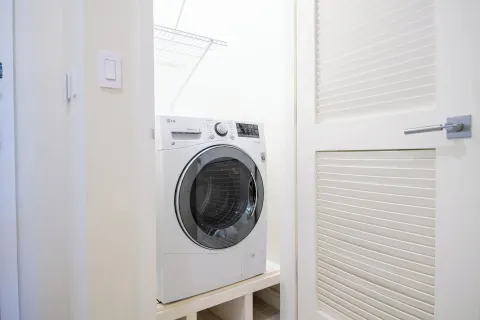 In-room laundry closet with front-loading appliance at Margaritaville Beach Resort - Nassau.