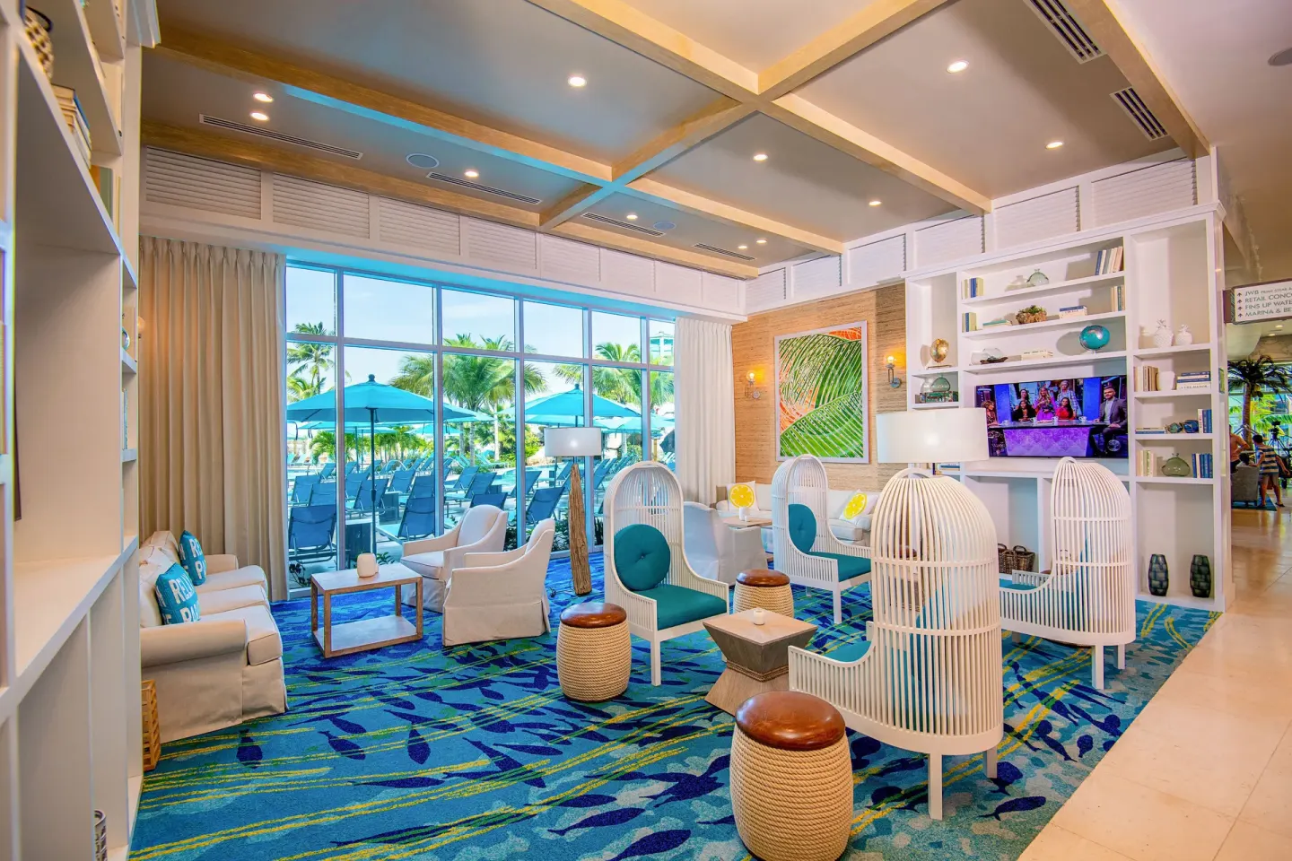 Resort lounge with white seating and pool windows at Margaritaville Beach Resort - Nassau.