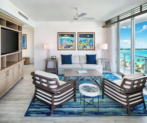 Suite living room with sofa, chairs, and balcony view at Margaritaville Beach Resort - Nassau.