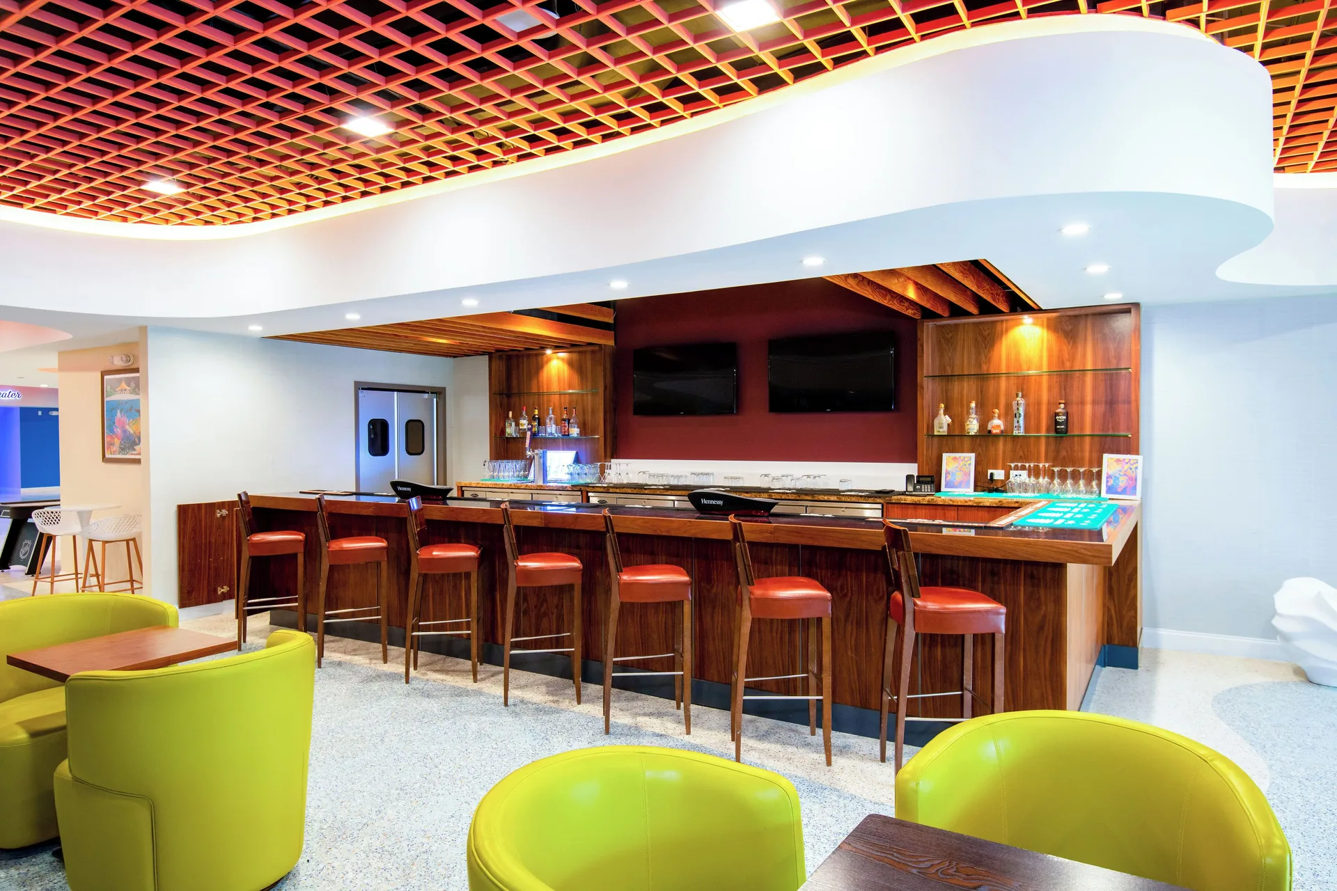 Wood bar with red stools in the entertainment area at Margaritaville Beach Resort - Nassau.