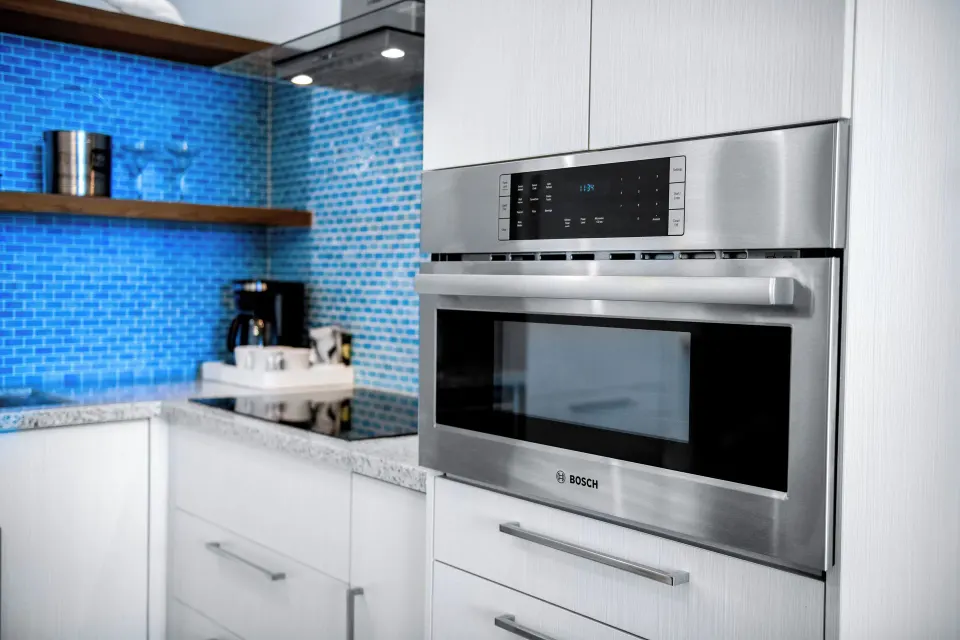 Suite kitchen at Margaritaville Beach Resort - Nassau with microwave, cooktop, and blue tile backsplash.