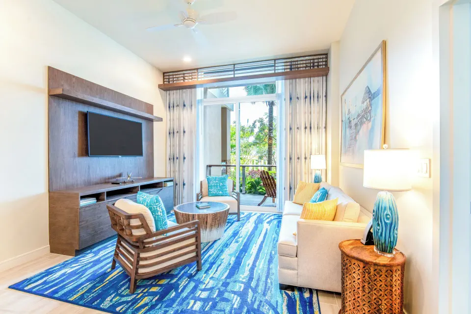 Suite lounge at Margaritaville Beach Resort - Nassau with sofa, TV wall, and balcony access.