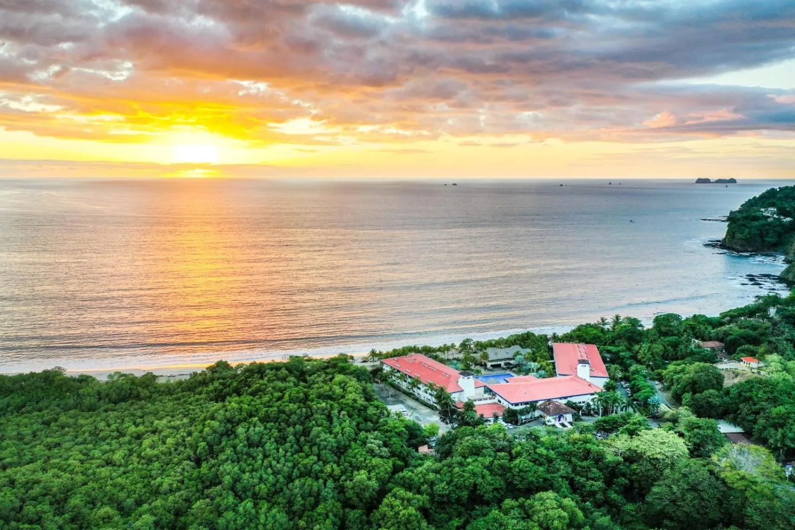 Aerial sunset view of the beach and resort buildings at Margaritaville Beach Resort Playa Flamingo.
