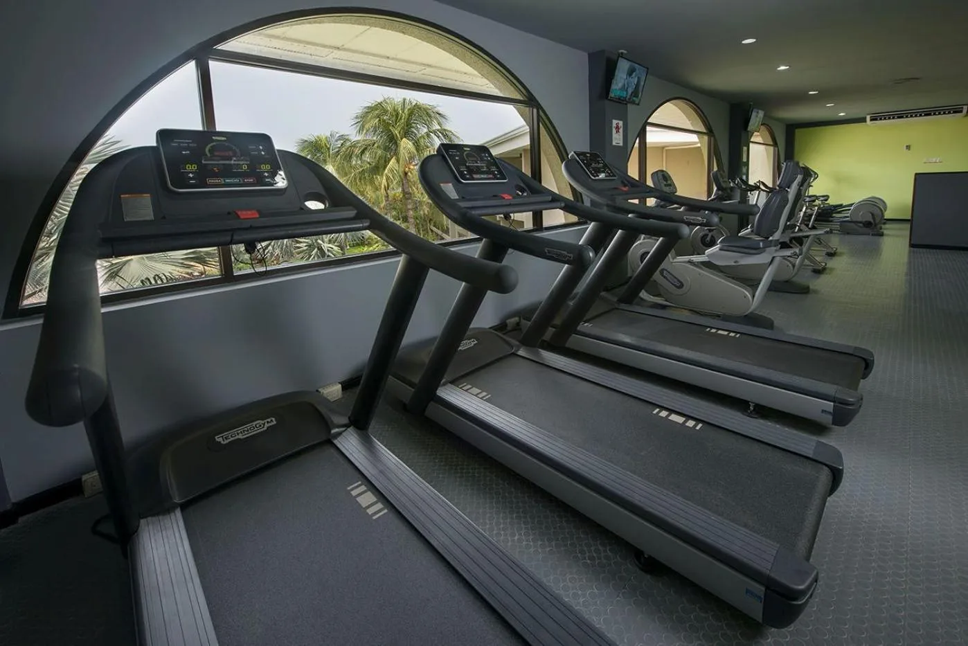 Treadmills lined up by arched windows at Margaritaville Beach Resort Playa Flamingo.