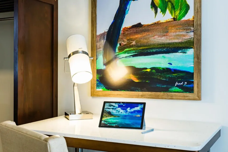 Guest room desk with lamp, tablet and tropical artwork at Margaritaville Beach Resort Playa Flamingo.