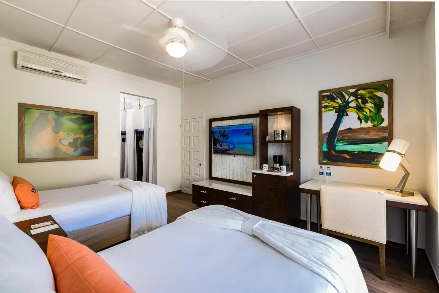 Two double beds, desk, TV and tropical art in a guest room at Margaritaville Beach Resort Playa Flamingo.
