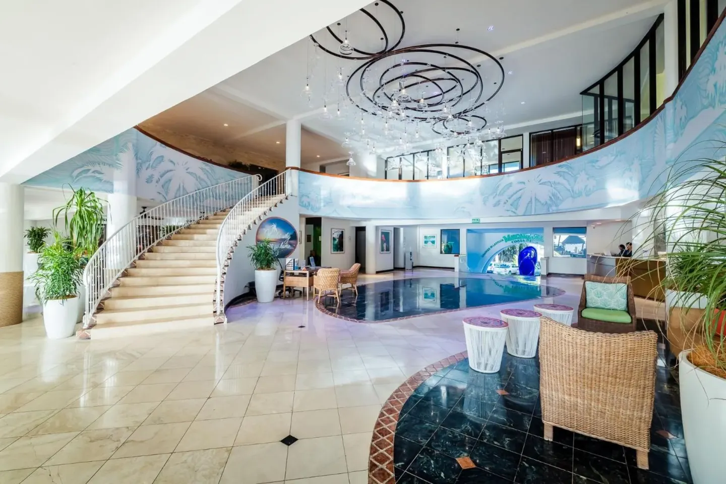 Lobby with curved staircase and wicker seating at Margaritaville Beach Resort Playa Flamingo.