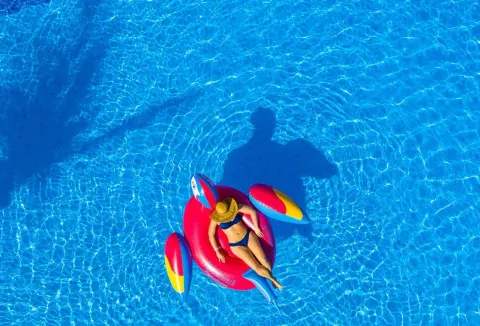 Guest floats on a red parrot pool raft at Margaritaville Beach Resort Playa Flamingo.