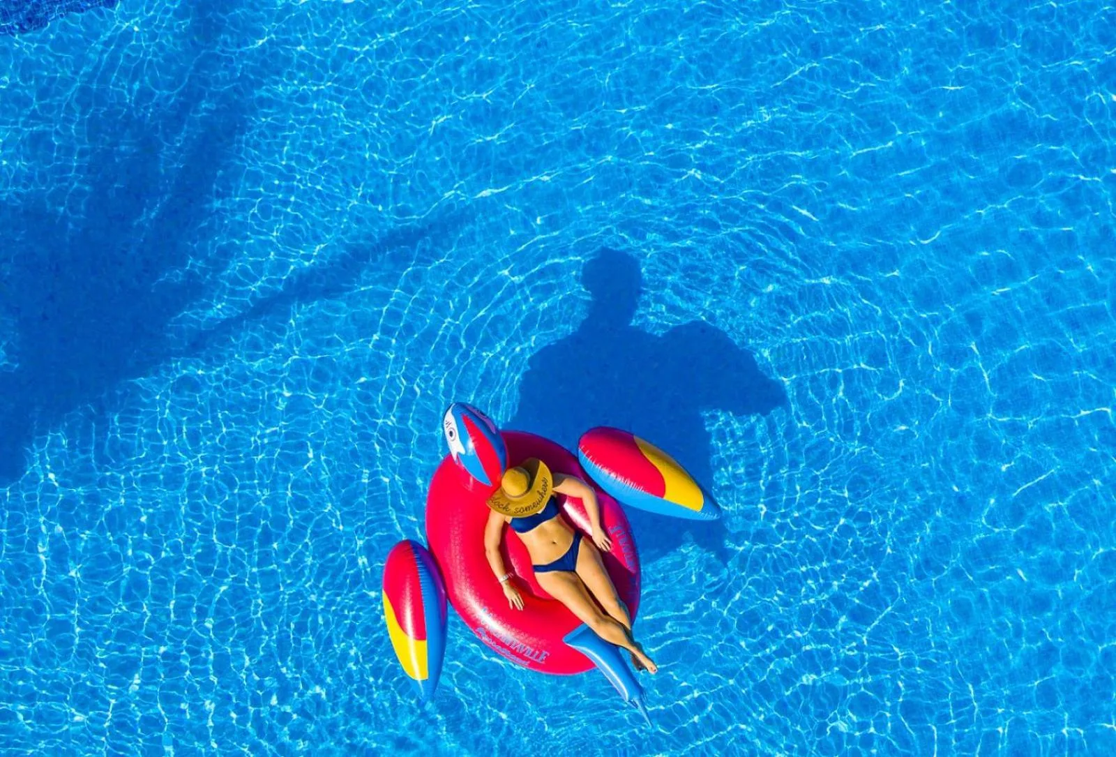 Guest floats on a red parrot pool raft at Margaritaville Beach Resort Playa Flamingo.