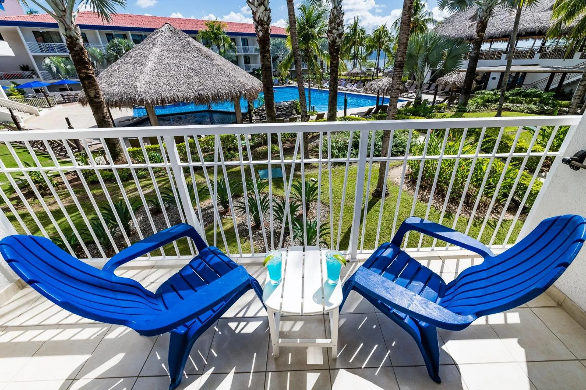 Blue balcony chairs overlook the pool and palm landscaping at Margaritaville Beach Resort Playa Flamingo.