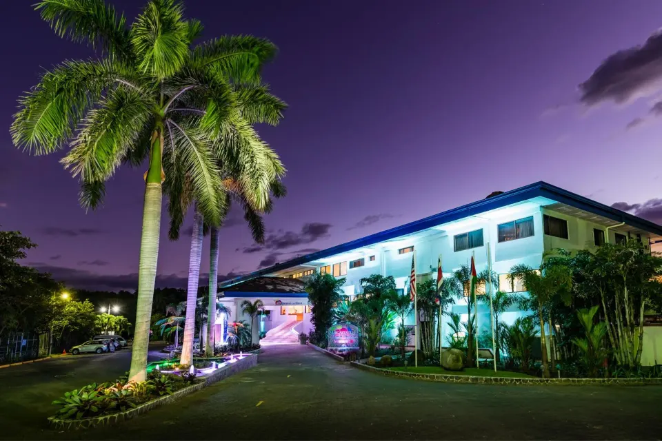 Nighttime resort entrance with lit palm trees at Margaritaville Beach Resort Playa Flamingo.